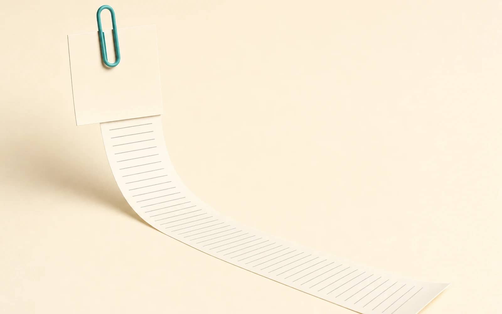 Paperclip AI review: a small teal paperclip holds a note, and a very long paper receipt unrolls from it across the ground